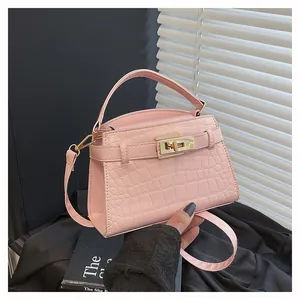 Detail shot of the pink crocodile texture and golden metal twist lock on the handbag