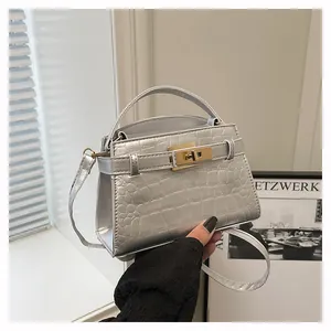 Close-up of silver crocodile embossed handbag with luxury gold metallic twist lock