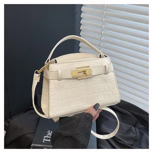 Detailed view of cream crocodile embossed mini handbag with gold-tone metal twist lock
