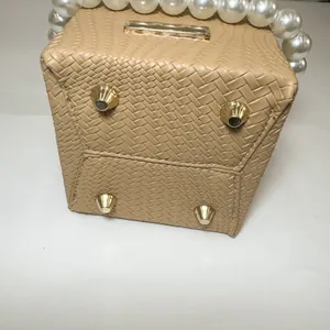 Close-up of beige woven bucket bag featuring pearl handle and gold metal feet on bottom