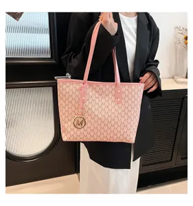 Detail of pink tote bag featuring M-letter print and golden logo charm hanging on strap