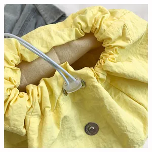 Dettaglio della coulisse e della fibbia magnetica in metallo su uno zaino in nylon giallo