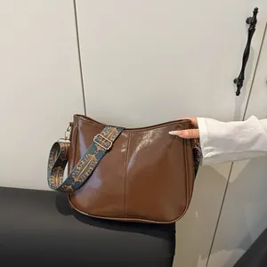 Brown faux leather saddle bag with vintage ethnic patterned wide strap and gold hardware
