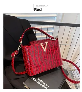 Detail of red crocodile pattern tote bag with gold V-shaped metal buckle and strap