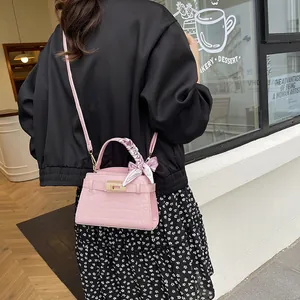 Pink crocodile-embossed handbag with floral scarf handle and gold twist-lock closure