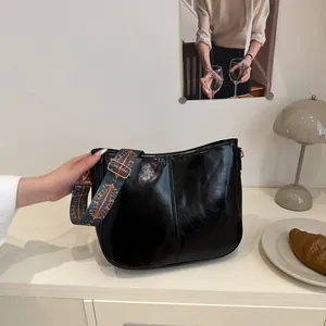 Chic black glossy leather tote bag with a colorful ethnic style wide woven shoulder strap