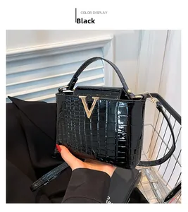 Detail of black crocodile texture tote bag with elegant golden V-shaped metal buckle clasp