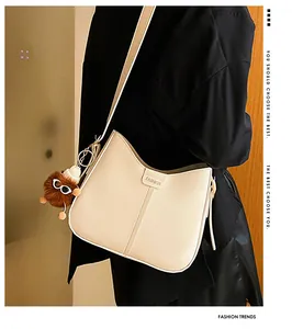Close-up of cream crossbody bag with vertical stitching and plush bear charm detail