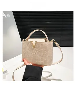 Detailed close-up of beige crocodile pattern tote bag with golden V-shaped metal hardware