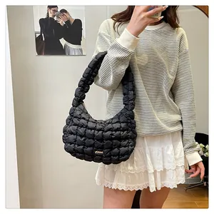 Détail d'un sac hobo matelassé noir avec une surface texturée moderne et bandoulière large