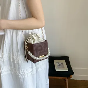 Brown woven leather bucket bag with pearl handle and golden chain shoulder strap