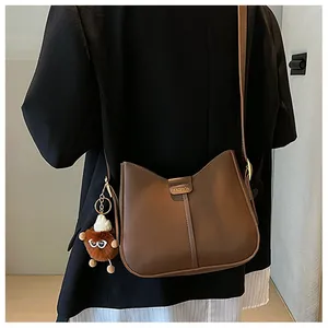 Detail of dark brown retro crossbody bag with fuzzy monster charm on a stylish model