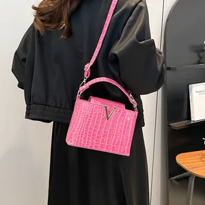 Pink crocodile-embossed tote bag with V-shaped gold hardware and adjustable strap