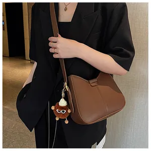 Brown leather saddle bag with fashion metal detail and cute plush doll pendant accessory