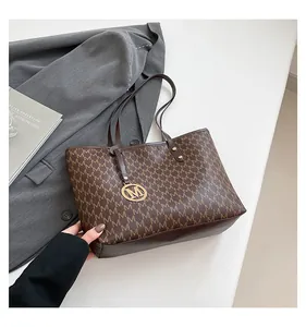 Detail of dark brown tote bag featuring texture leather and gold M letter pendant