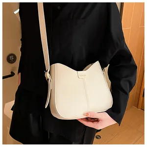 Detail of cream crossbody bag with wave opening and fashion plaque on black outfit