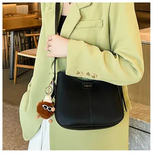 Detail of black leather saddle bag with gold metal plaque and cute plush doll pendant