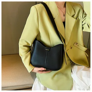 Detail of minimalist black leather crossbody bag with fashion gold plate on a model