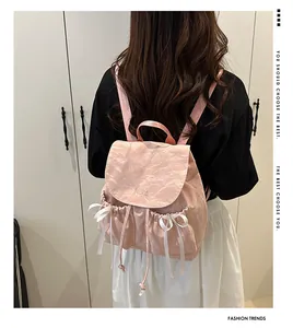 Detailed view of pink backpack with unique pleated texture and white ribbon bows