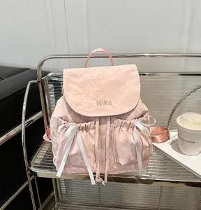 Detail of pink backpack featuring Nika embroidery, ribbon bows, and crinkle texture fabric