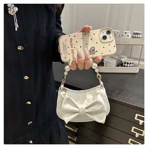 Close-up of elegant white handbag featuring a large bow and decorative pearl handle