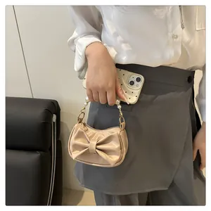 Mini cream handbag featuring a large bow and elegant white pearl handle details