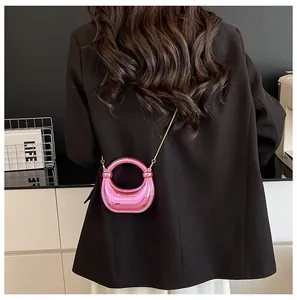 Mini borsa rosa metallizzato con manico rotondo e catena dorata indossata su un blazer nero