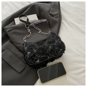 Détail de fleurs 3D en tulle noir sur un sac à bandoulière avec chaîne métallique