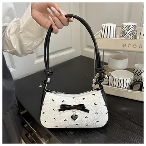 Gros plan du tissu jacquard blanc avec nœuds noirs et pendentif cœur sur le sac à main