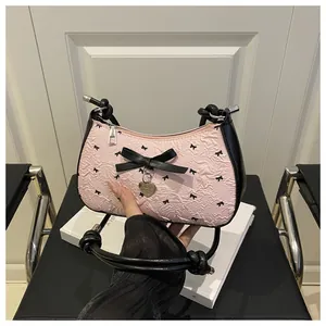 Gros plan du sac hobo rose à nœuds avec jacquard texturé et détail de pendentif cœur