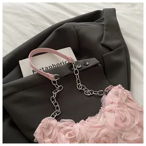 Gros plan du sac à fleurs en résille rose clair avec bandoulière chaîne métallique