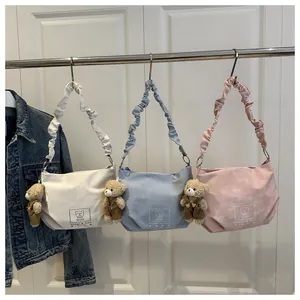 Detail showing plush bear pendant and embroidered logo on stylish pleated strap bags