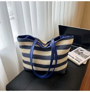 Close-up of the navy striped woven tote bag featuring glossy blue faux leather handles