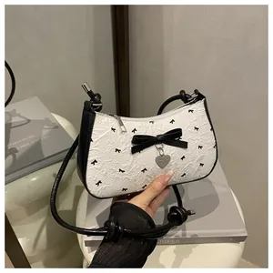 Détail du sac en jacquard blanc avec motifs nœuds noirs et pendentif cœur en métal