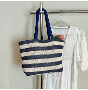 Detail of woven straw tote bag featuring navy stripes and durable leather straps