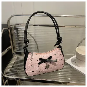 Détail du sac baguette rose froncé avec nœud noir et pendentif cœur métallique