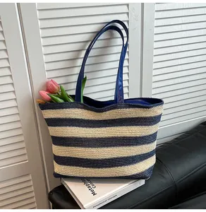 Detailed weave of blue and beige striped straw tote with premium blue leather handles