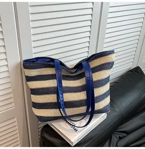 Detail of navy striped woven tote bag featuring durable blue leather handles and lining