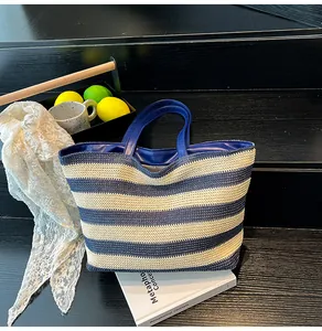 Detail of blue striped woven tote bag featuring leather handles and interior lining
