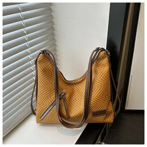 Detalle del bolso tote con tejido de espiga, asas de cuero y parche de logotipo de moda