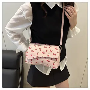 Détail du sac demi-lune rose avec imprimés cerises rouges et finitions dorées