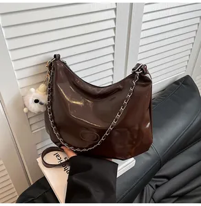 Detail of dark brown patent leather tote with silver chain and white teddy charm