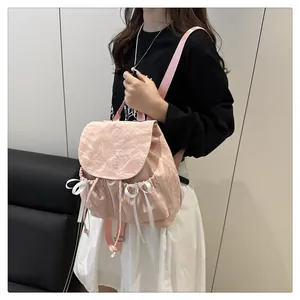Detail of pink nylon backpack featuring white ribbon bows and embroidered logo on flap
