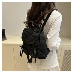Detail of black wrinkled nylon backpack featuring ribbon bows and drawstrings