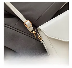 Gros plan des boucles dorées et des coutures précises sur le sac à bandoulière blanc
