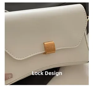 Détail du fermoir métallique doré texturé sur le sac à bandoulière minimaliste blanc