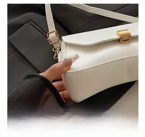 Détail du sac baguette blanc avec boucle dorée et coutures de haute précision