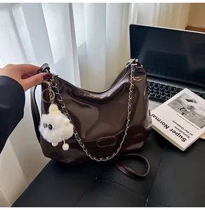 Detail of glossy coffee hobo bag with silver chain and cute plush sheep charm