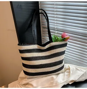 Close-up of black and white striped woven tote bag with black leather handle and floral decor
