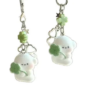 Pair of white flocked bear keychains with green clover charms and silver lobster clasps